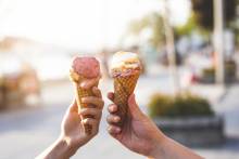 two people holding out ice cream cones